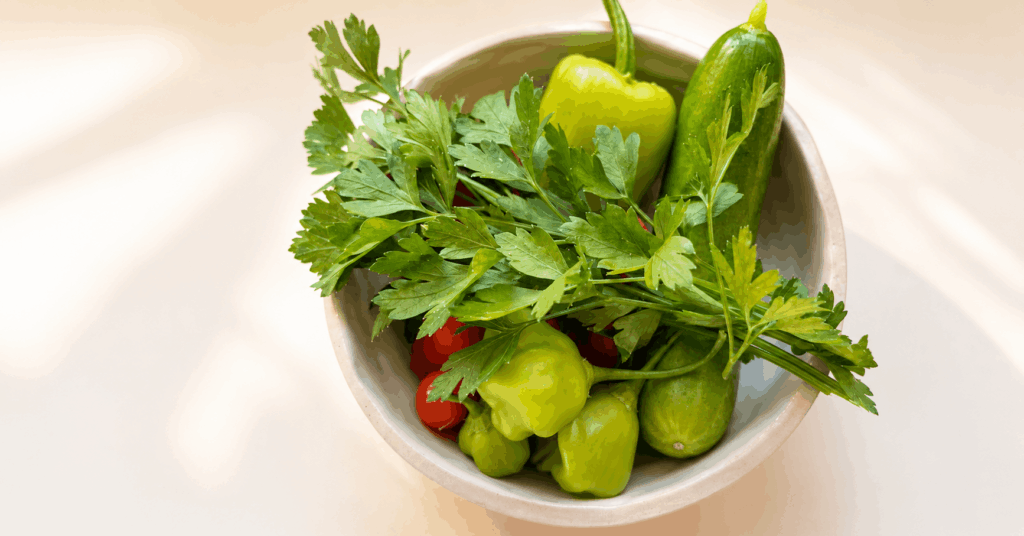 Frische Gurken, grüne Paprika, Tomaten und Petersilie in einer Keramikschüssel